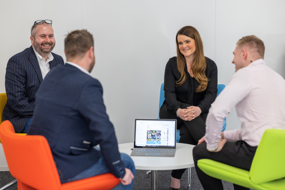 Team meeting with four people around laptop