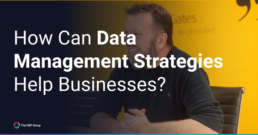 Smiling Managed IT Support Engineer sitting at a desk with a yellow background and bold text overlay that reads ‘How Can Data Management Strategies Help Businesses?
