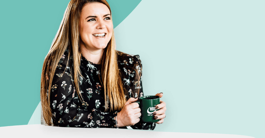 Green background with woman in the forefront holding a green mug and smiling