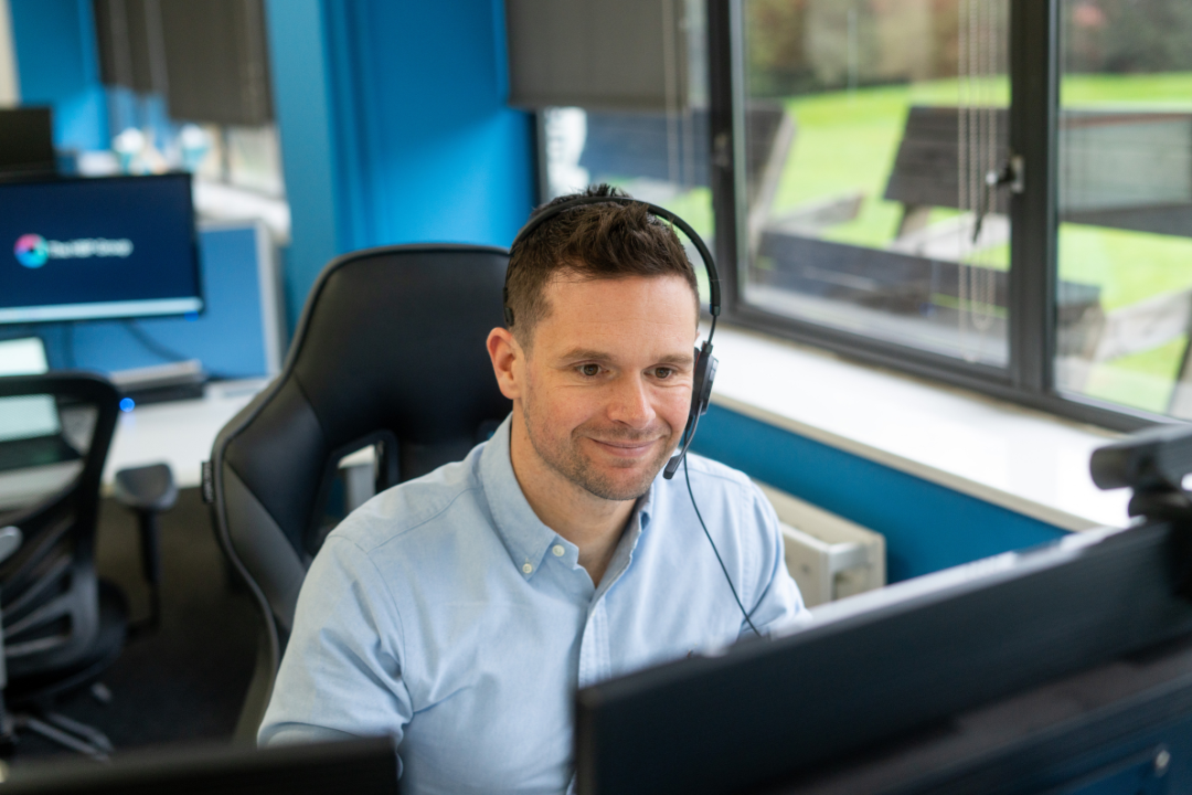 Man sat behind computer with headset on