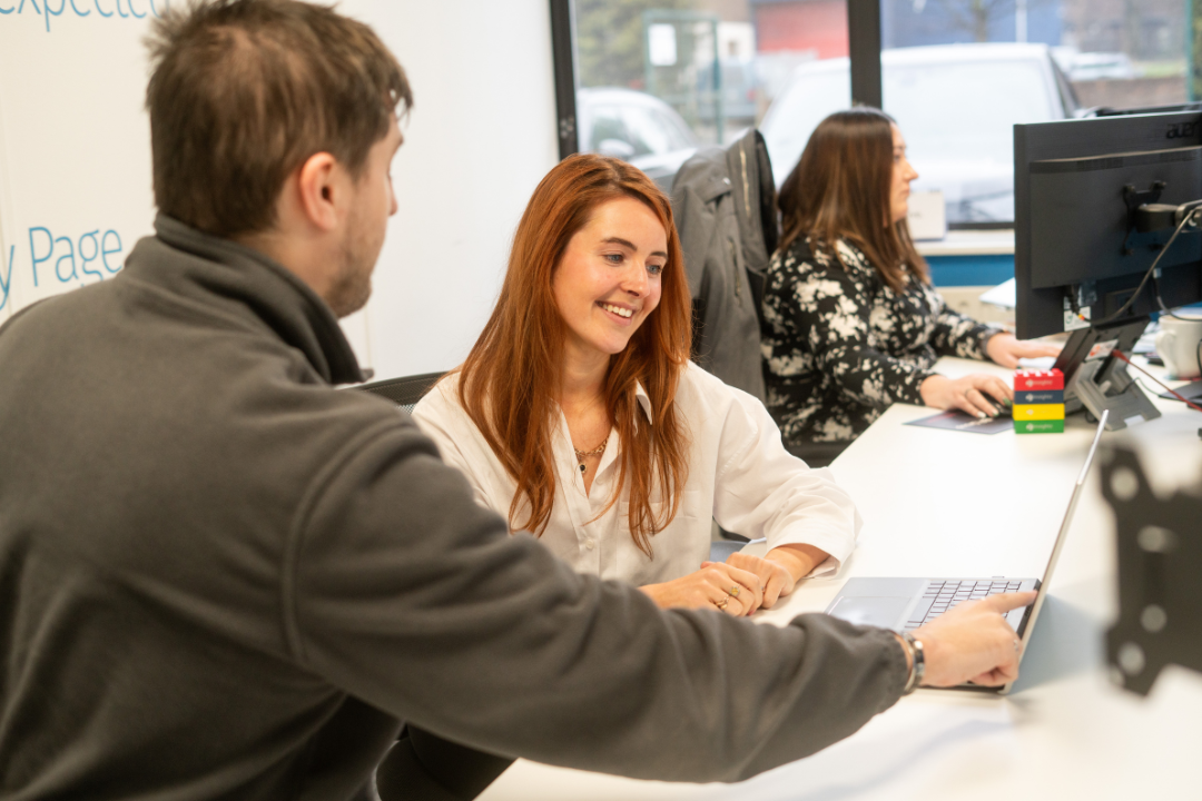 Man sat next to woman pointing to laptop screen