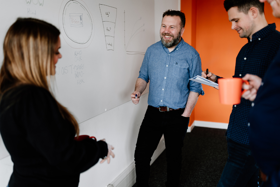 Man Stood in Front of Whiteboard Smiling