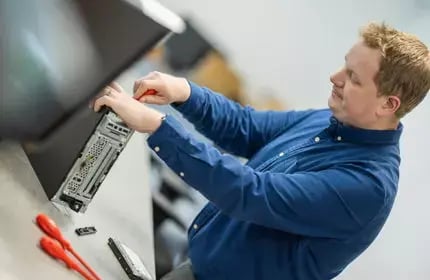 IT-Procurement-Man-in-Blue-Shirt-Fixing-Computer-Tower-with-Screwdriver-430x280